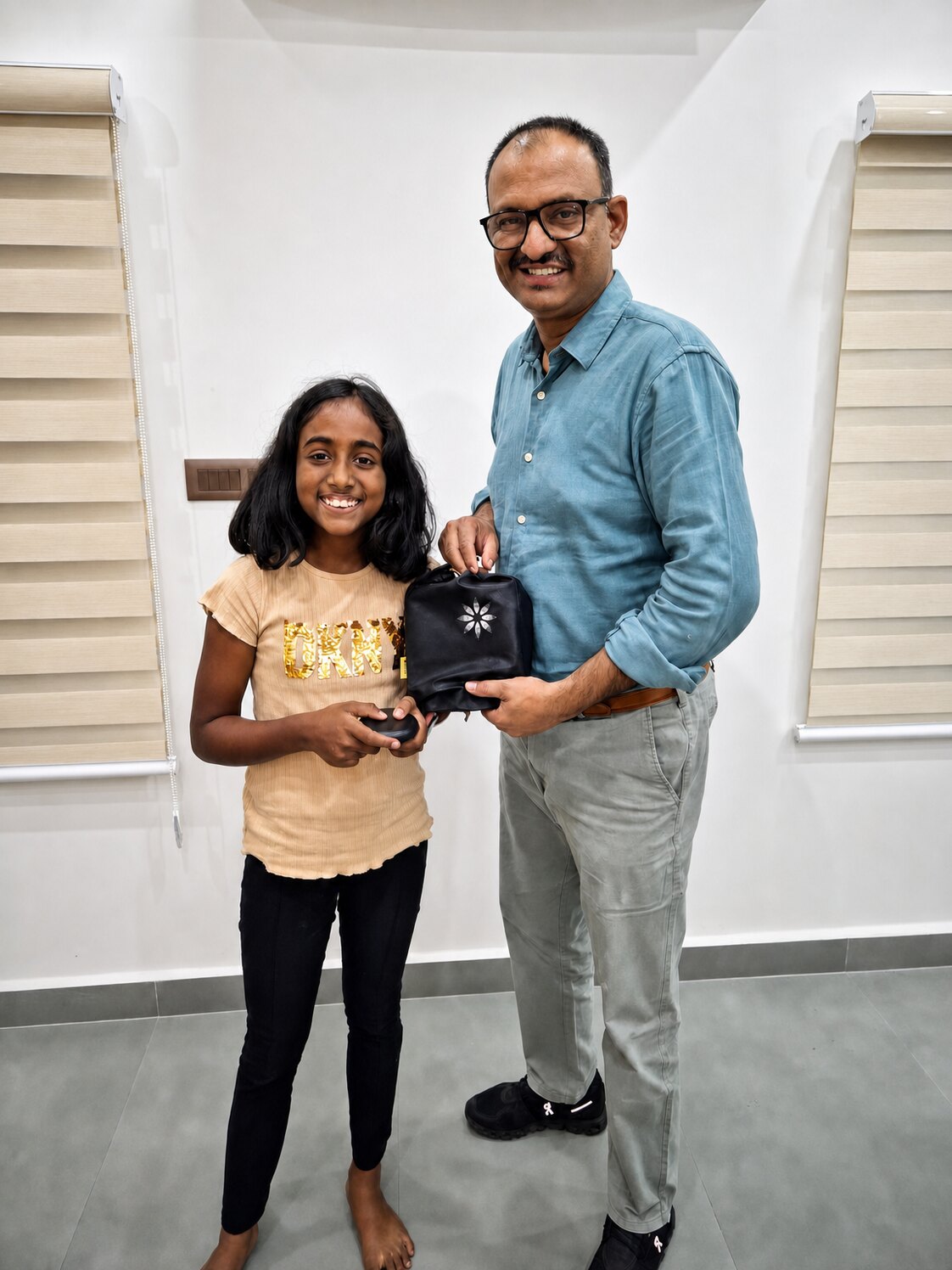 A young patient at Align Dental Care holding her new aligner case beside Prof. Dr S. Srinivas.
