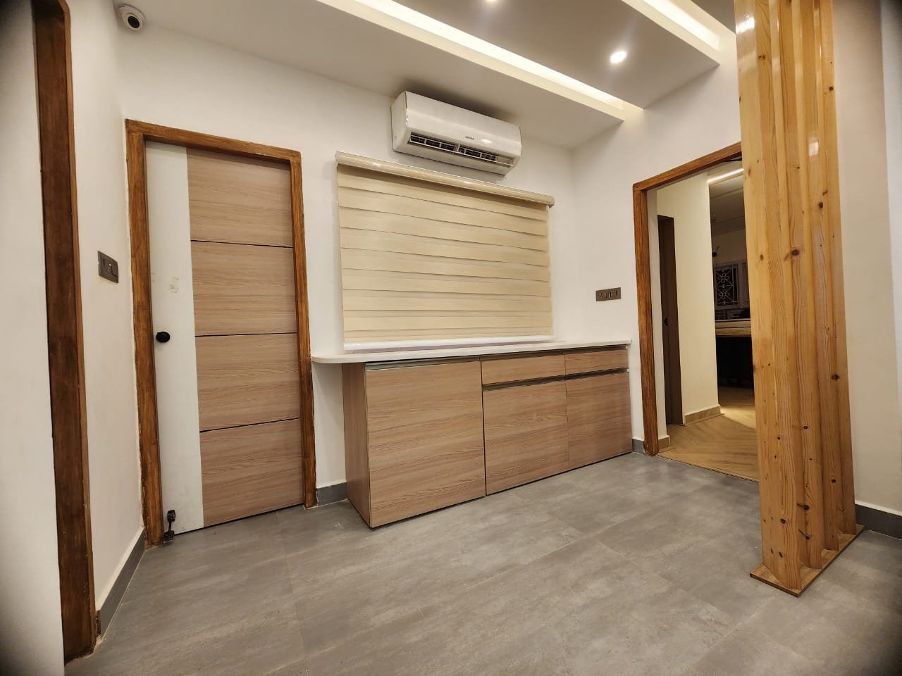 The corridor the treatment rooms open off, with timber cabinetry along one wall, a panelled door and a further room beyond.
