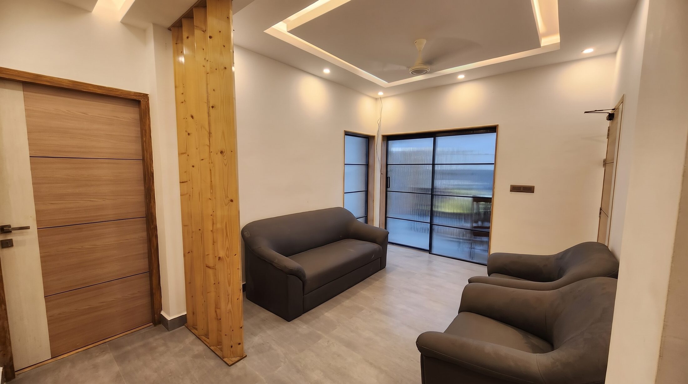 The waiting room at Align Dental Care: dark armchairs, a timber-clad column, a cove-lit ceiling and black-framed glazing onto the balcony.