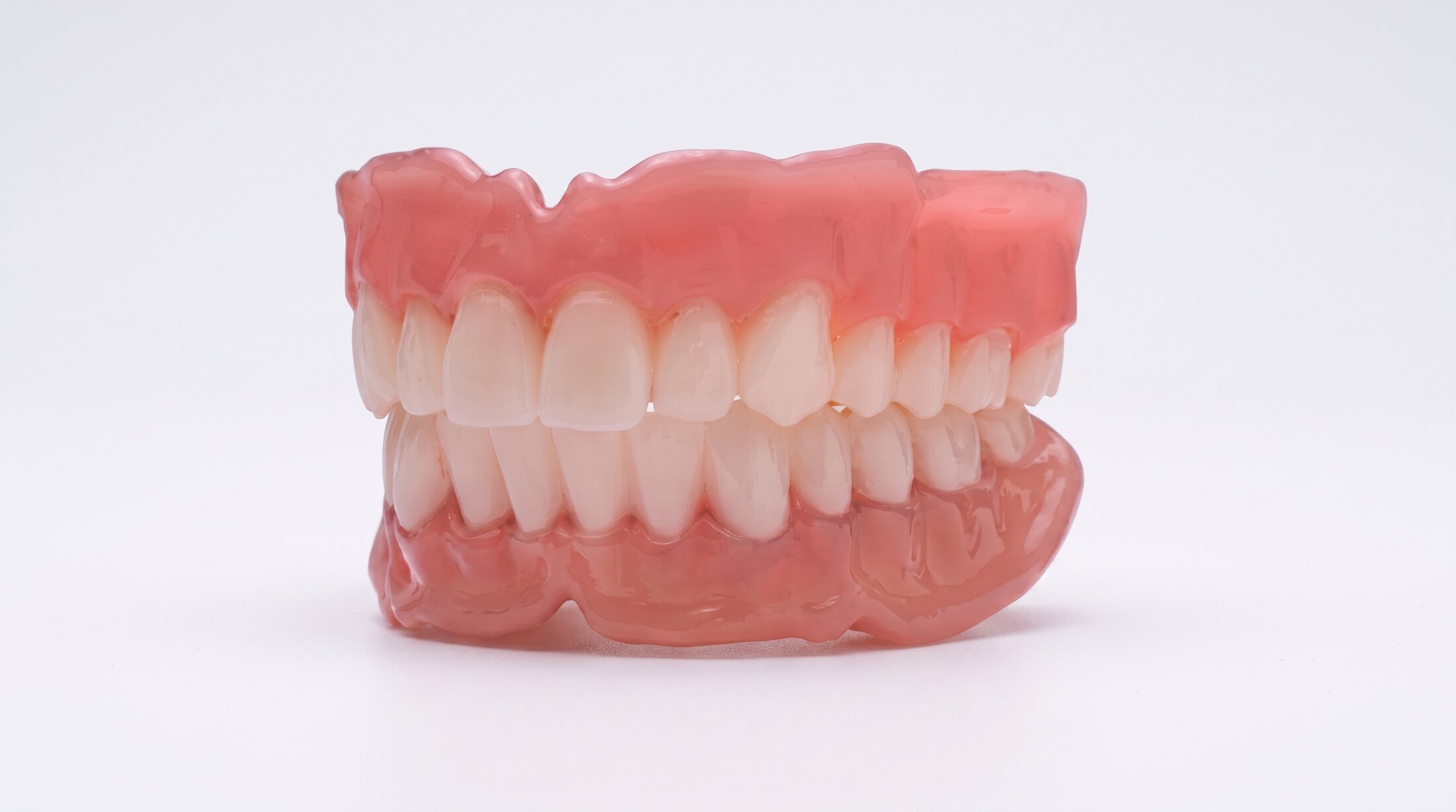 A complete upper and lower denture, the two closed together on a plain ground.